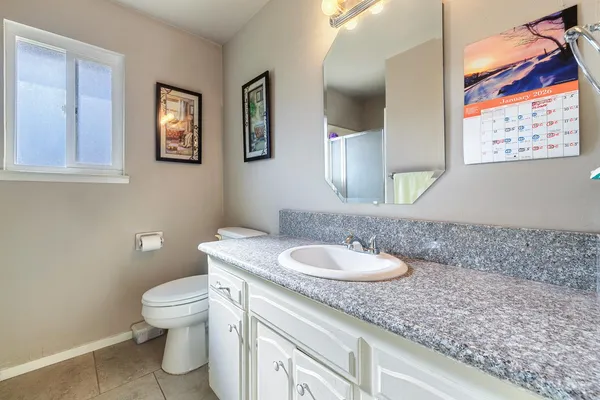 a bathroom with a granite countertop toilet sink and mirror