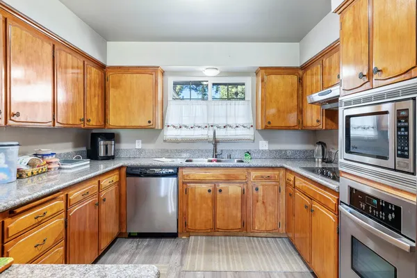 a kitchen with stainless steel appliances granite countertop wooden cabinets a sink and a stove