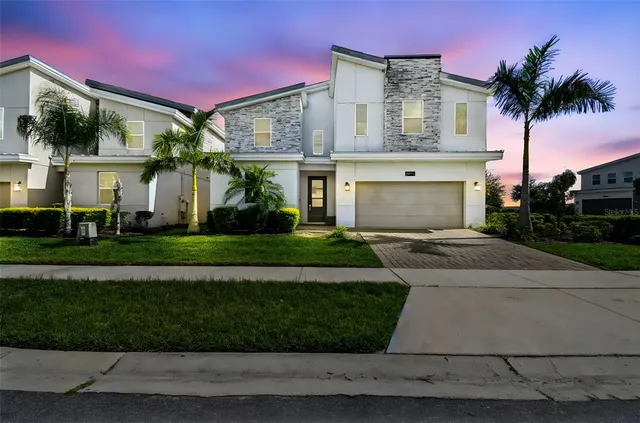 a front view of a house with a garden and palm tree