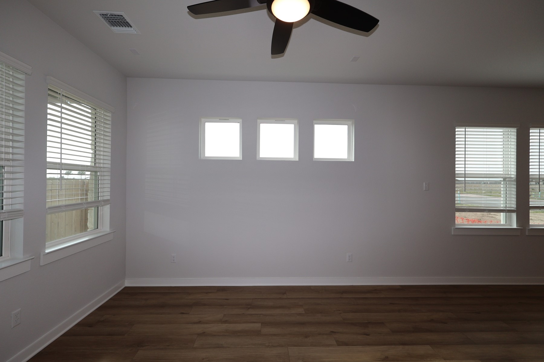304 Emerie Way Georgetown, TX 78626 - Photo 5 of 15 an empty room with wooden floor cabinet and windows