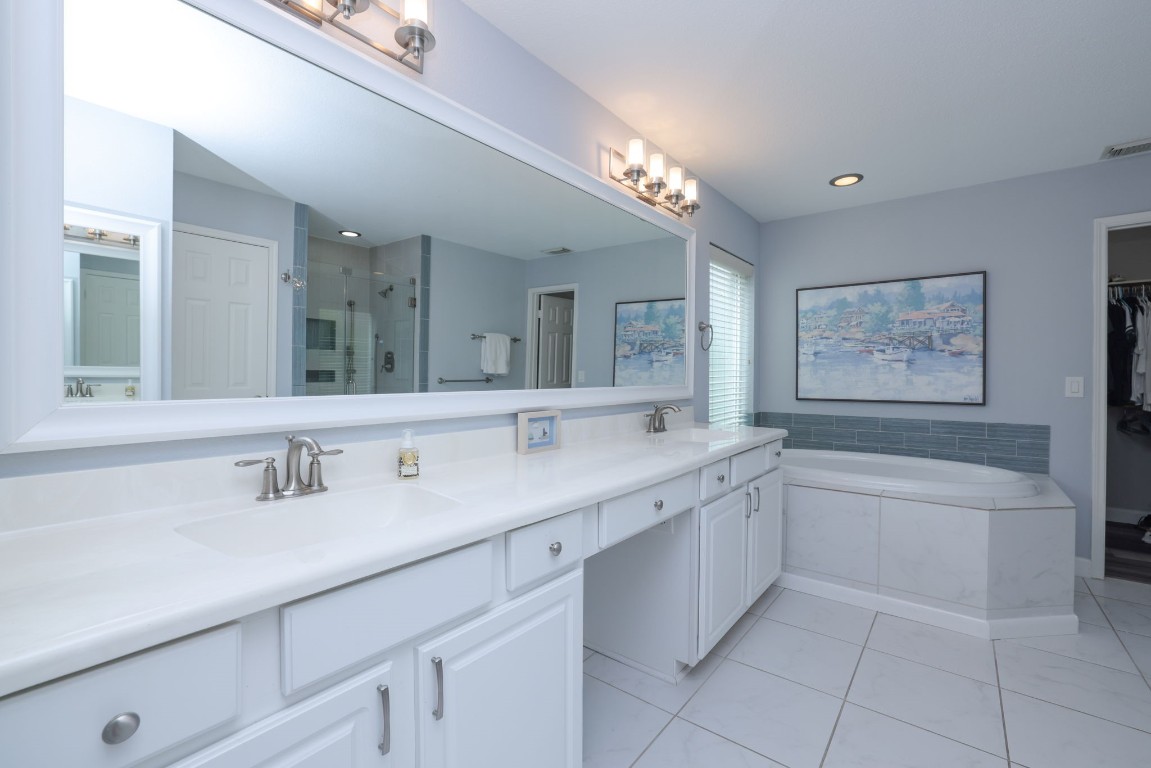 8827 Stoney Bend Drive Spring, TX 77379 - Photo 24 of 39 a bathroom with a granite countertop sink a large mirror a bathtub and next to a window