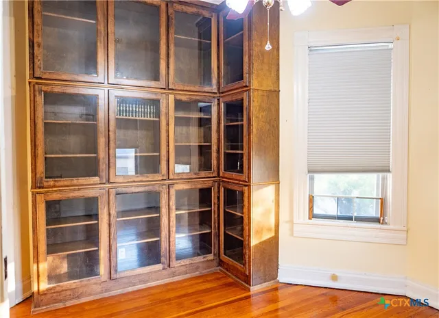 a view of an empty room with wooden floor and a window