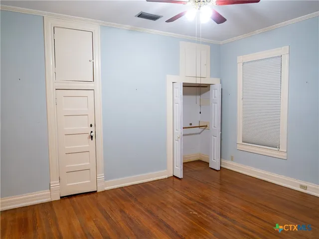 an empty room with wooden floor cabinet and windows