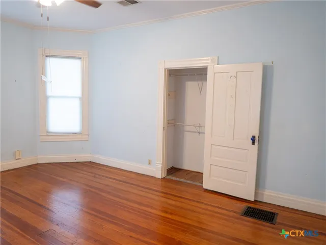 an empty room with wooden floor cabinet and windows
