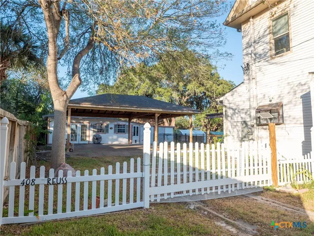 a view of a house with a small yard and wooden fence