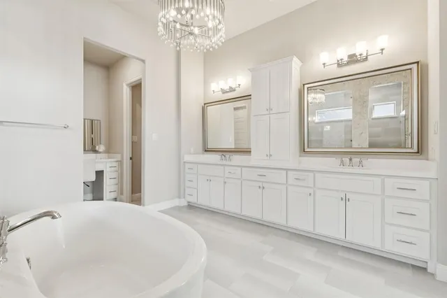 a spacious bathroom with a double vanity sink a mirror a window and a bathtub