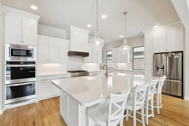 a kitchen with stainless steel appliances kitchen island granite countertop a stove a refrigerator and a microwave