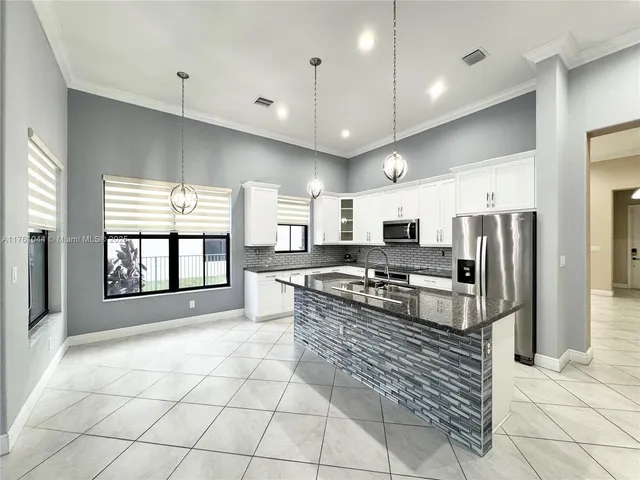 a large kitchen with stainless steel appliances granite countertop a stove a sink and a refrigerator
