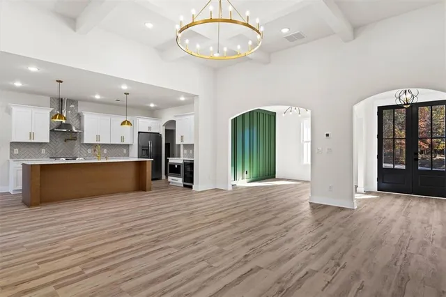 an empty room with wooden floor chandelier and windows