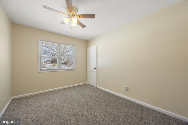an empty room with a ceiling fan and a window