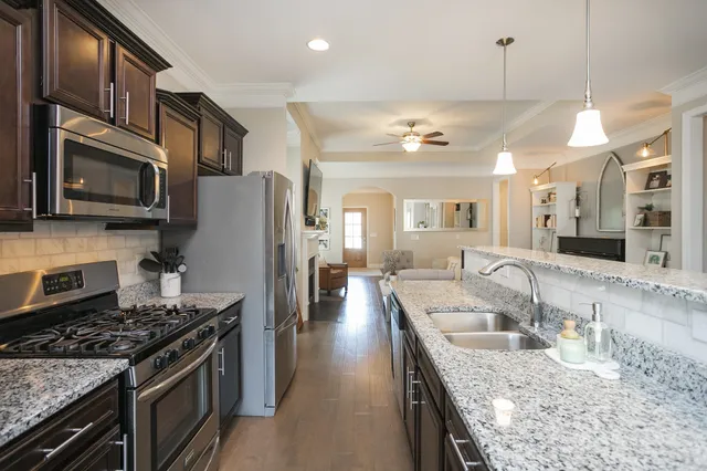 a kitchen with stainless steel appliances granite countertop a stove top oven a refrigerator a sink and dishwasher
