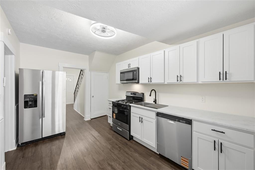 127 Duffland Street Pittsburgh, PA 15210 - Photo 18 of 36 a kitchen with stainless steel appliances granite countertop white cabinets a sink a stove a refrigerator and dishwasher with wooden floor