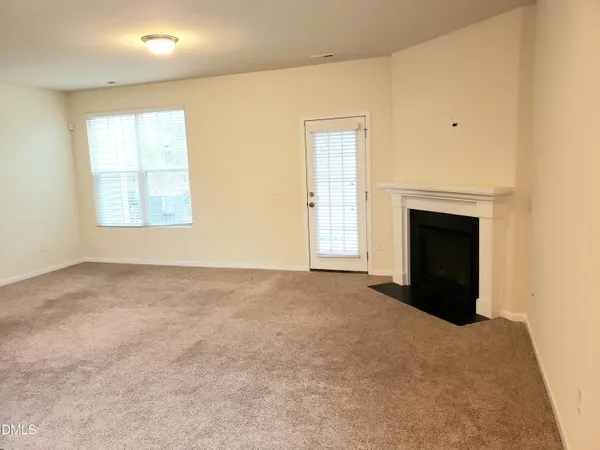 an empty room with windows and fireplace