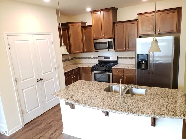 a kitchen with stainless steel appliances granite countertop a refrigerator a stove and a sink