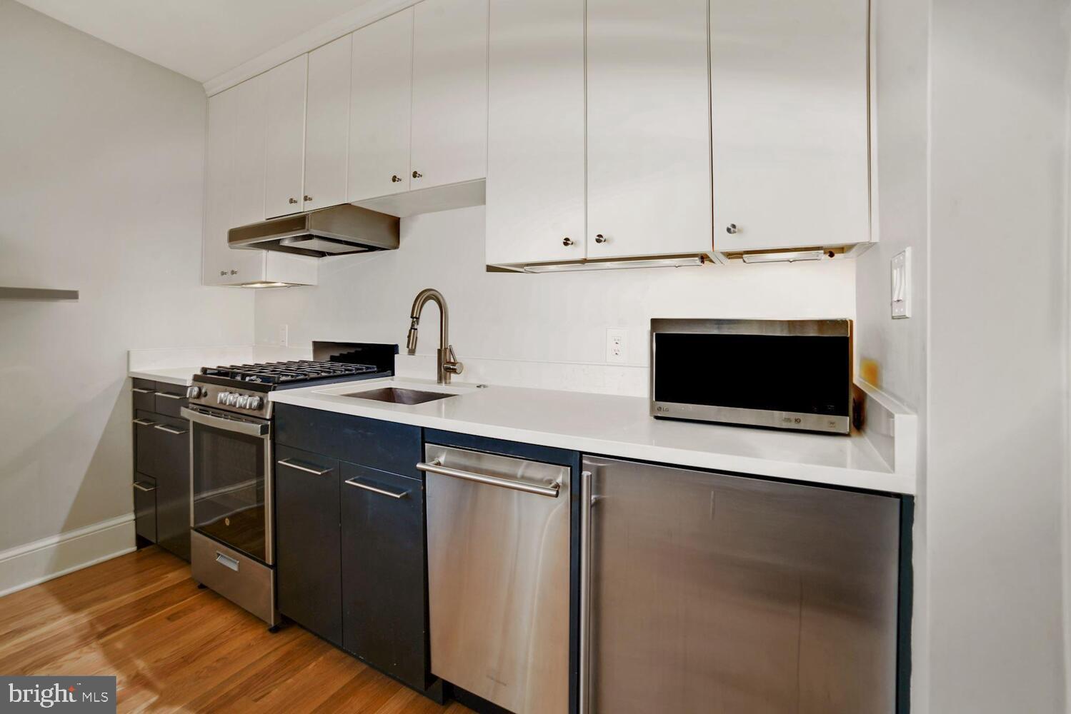 3348 Prospect Street Northwest, Unit 1 Washington, DC 20007 - Photo 3 of 16 a kitchen with stainless steel appliances a stove a microwave and white cabinets