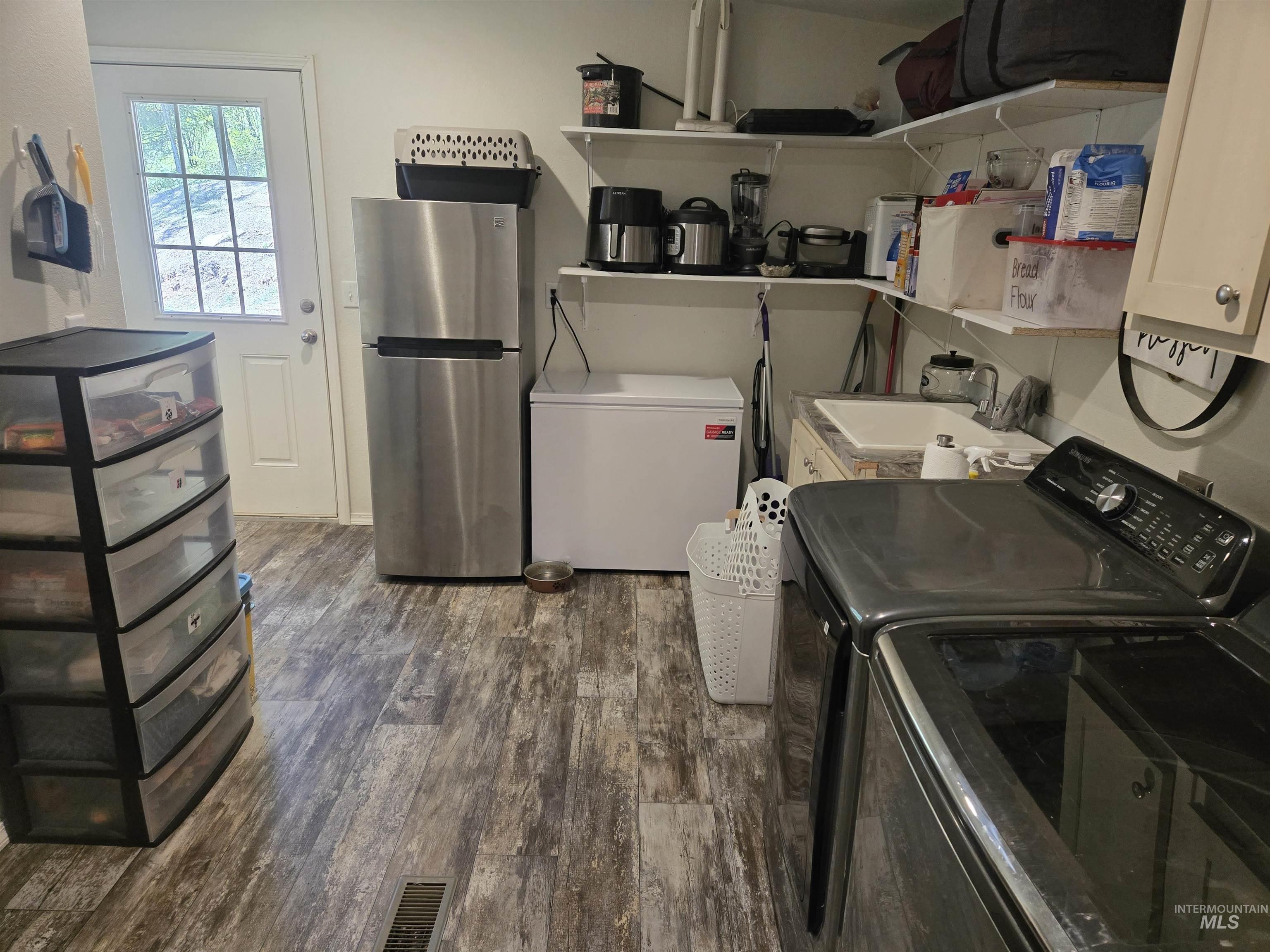 174 Konkolville Road Orofino, ID 83544 - Photo 28 of 43 Laundry area featuring wood-finish flooring, a utility sink with base cabinetry, and open shelving storage