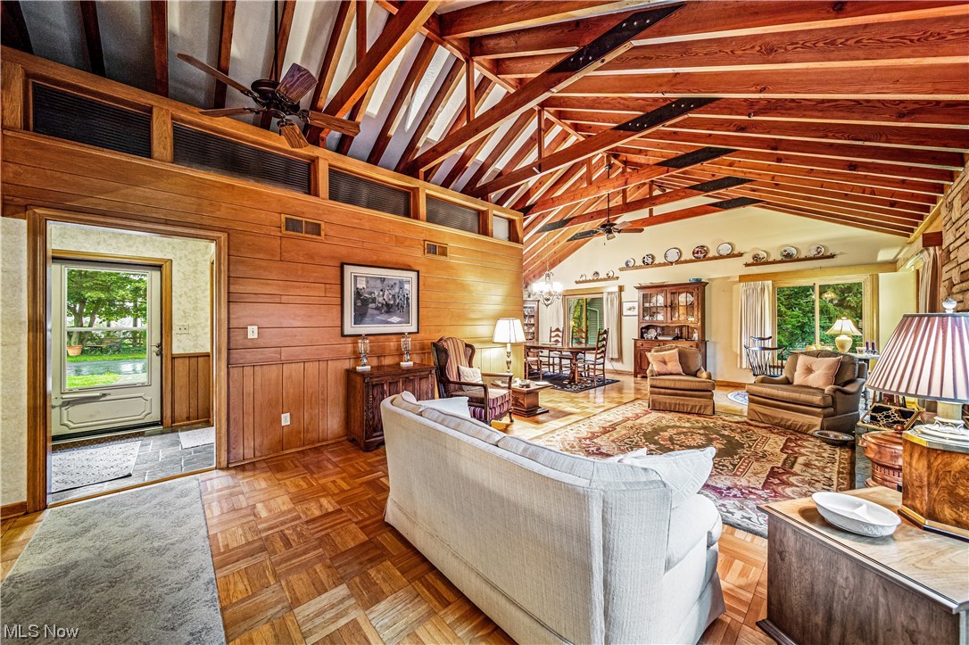 35510 Ridge Road Willoughby, OH 44094 - Photo 11 of 35 Living room featuring wooden walls, light parquet flooring, vaulted ceiling with beams, a high ceiling, and ceiling fan