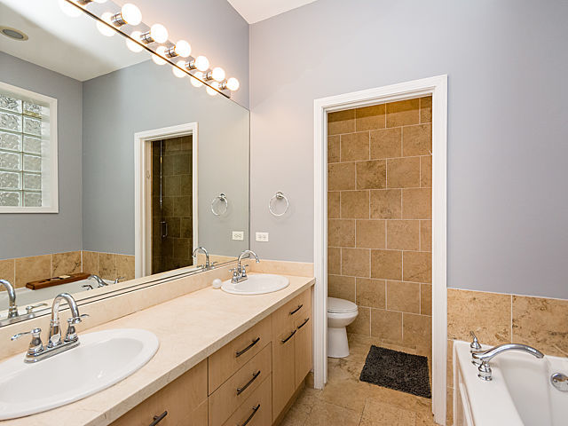 2127 West Rice Street, Unit 4E Chicago, IL 60622 - Photo 14 of 23 a bathroom with a double vanity sink toilet and shower