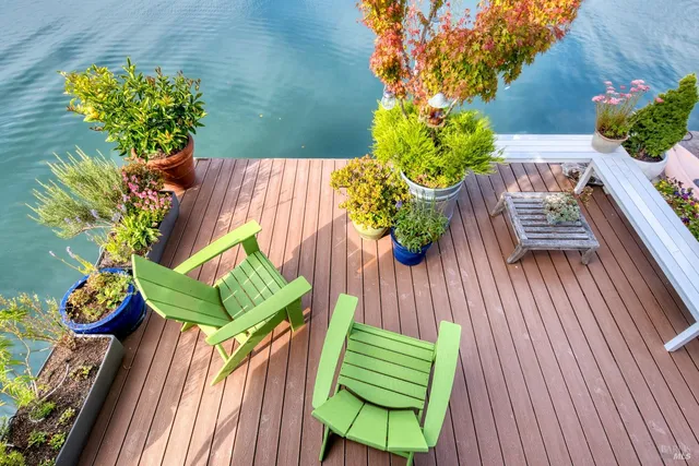 a view of a balcony with chairs potted plants and wooden fence
