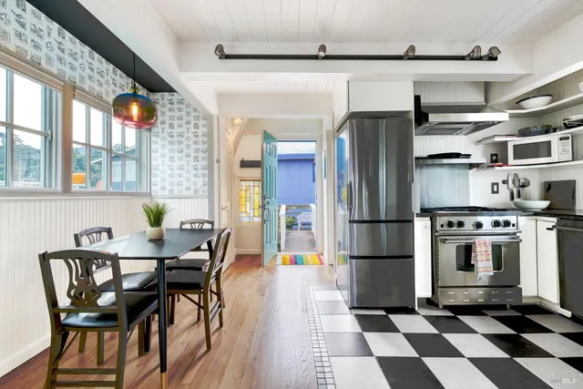 a kitchen with stainless steel appliances a refrigerator a stove a dining table and chairs with wooden floor