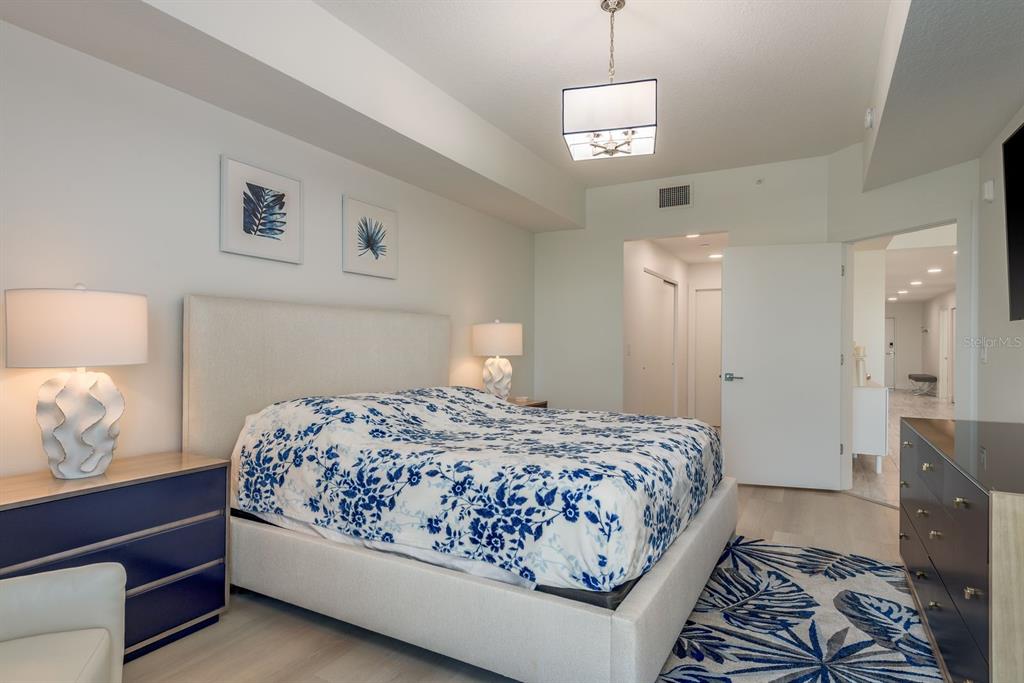 415 Island Way, Unit 402 Clearwater Beach, FL 33767 - Photo 19 of 35 a bedroom with a bed and a lamp on dresser