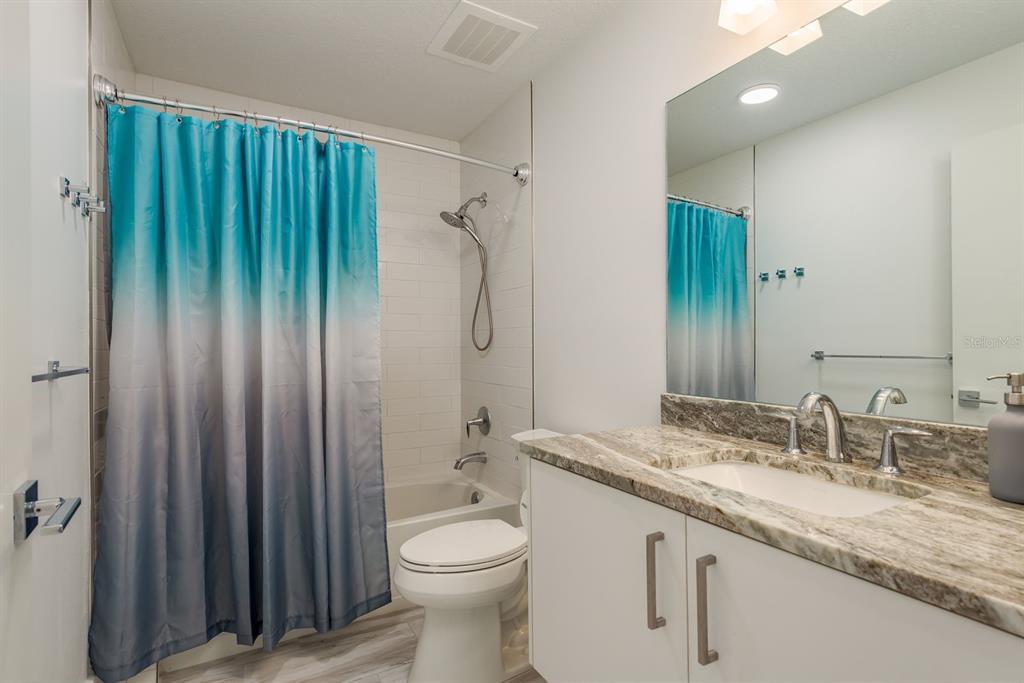 415 Island Way, Unit 402 Clearwater Beach, FL 33767 - Photo 26 of 35 a bathroom with a granite countertop sink toilet and shower