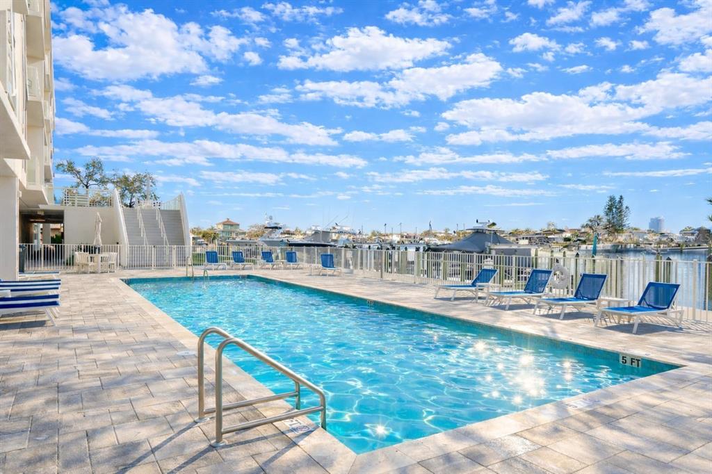 415 Island Way, Unit 402 Clearwater Beach, FL 33767 - Photo 29 of 35 a view of a swimming pool with a lawn chairs