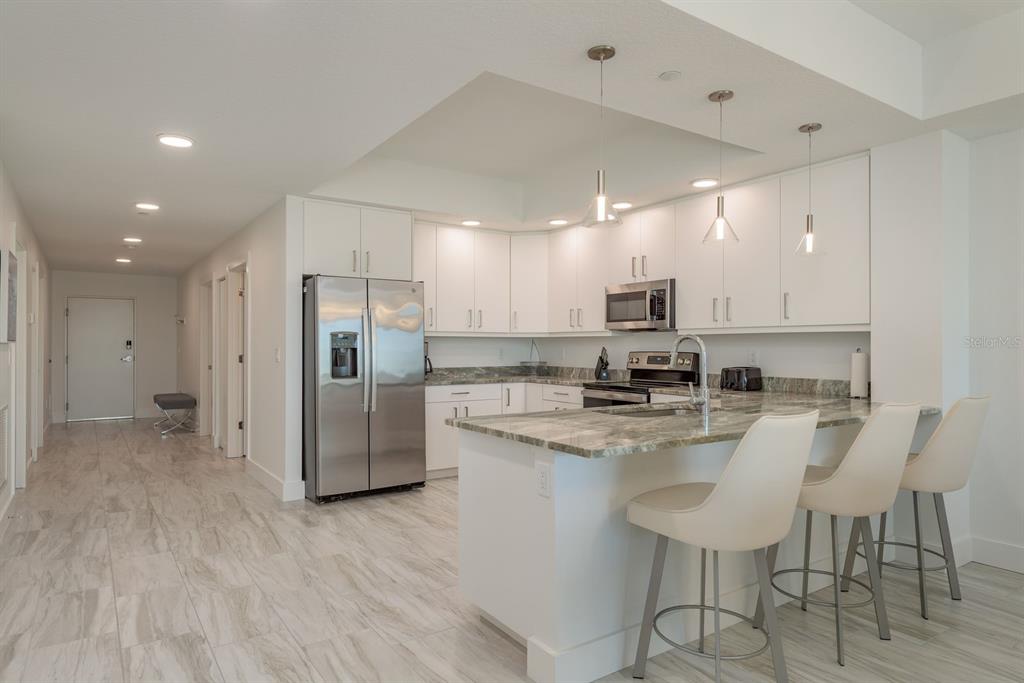 415 Island Way, Unit 402 Clearwater Beach, FL 33767 - Photo 9 of 35 a kitchen with refrigerator and cabinets