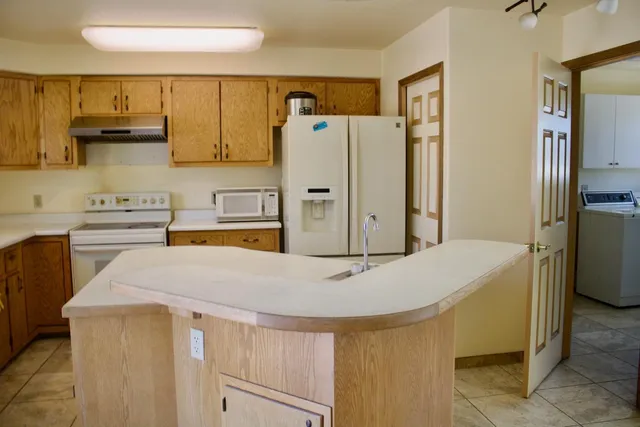 a kitchen with stainless steel appliances a refrigerator a sink and white cabinets