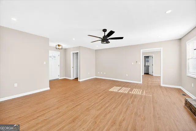 a view of a livingroom with a fireplace a ceiling fan and wooden floor