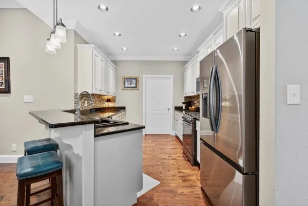 a kitchen with stainless steel appliances granite countertop a refrigerator and a stove top oven
