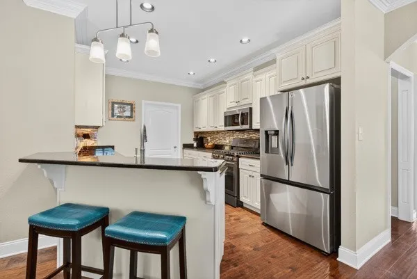 a kitchen with stainless steel appliances a refrigerator a sink a stove a dining table and chairs