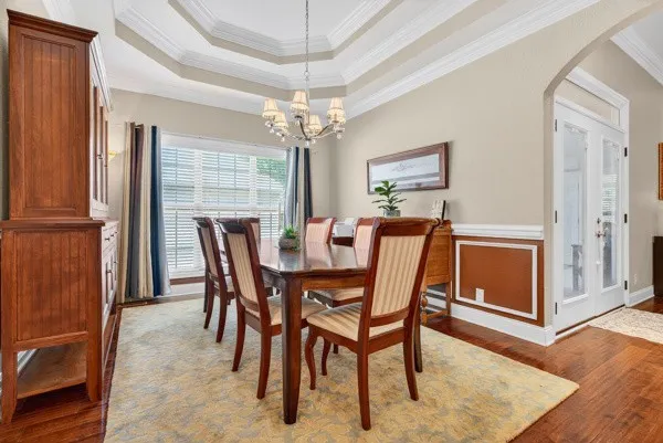 a dining room with furniture a chandelier and wooden floor