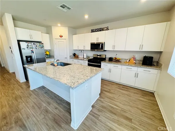 a kitchen with granite countertop a sink a counter top space cabinets and stainless steel appliances