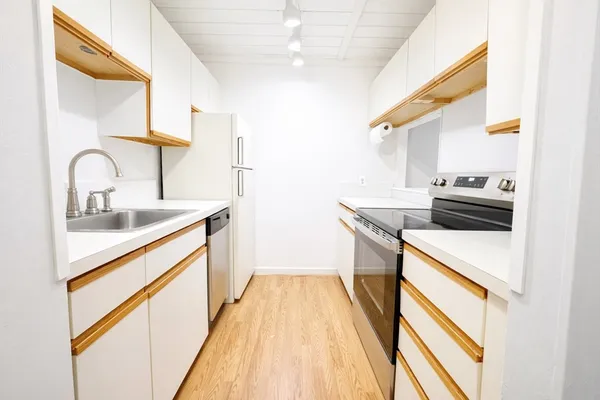 a kitchen with a sink a stove top oven and cabinetry