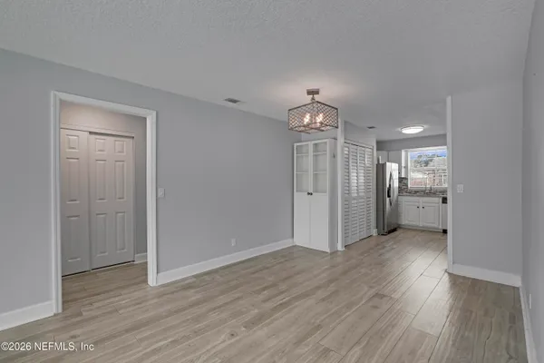 a view of a hallway with wooden floor and a kitchen