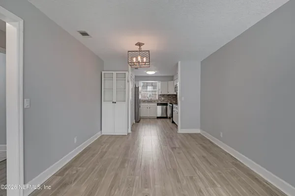 a view of a hallway with wooden floor and a kitchen