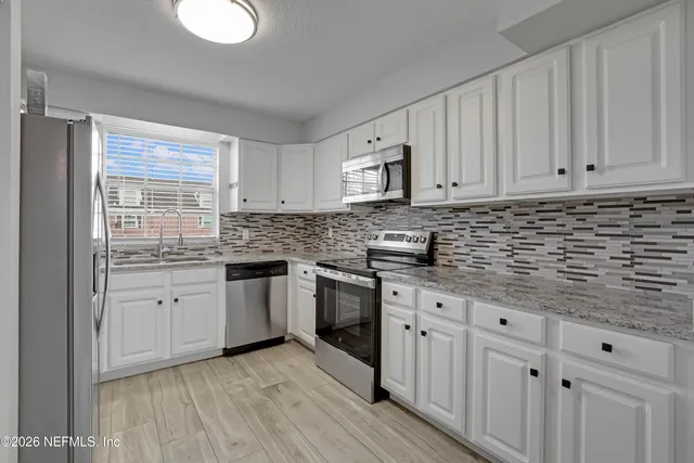 a kitchen with stainless steel appliances granite countertop a stove a sink and white cabinets