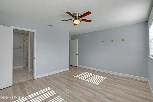a view of an empty room with window and wooden floor