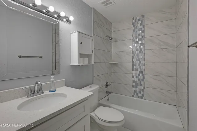 a bathroom with a granite countertop sink a toilet and shower