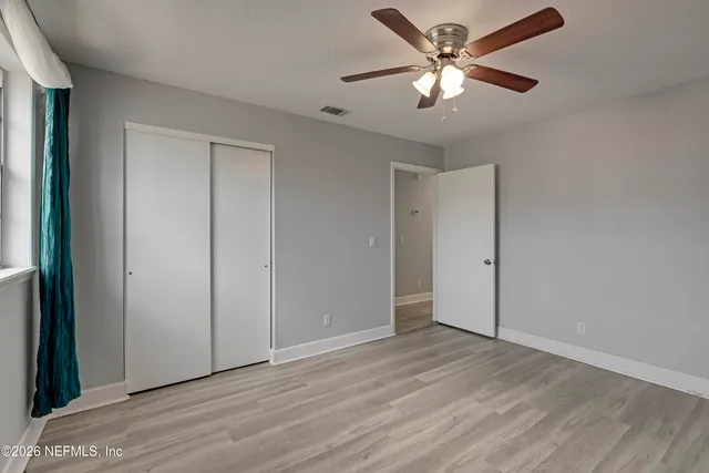 an empty room with wooden floor and a ceiling fan