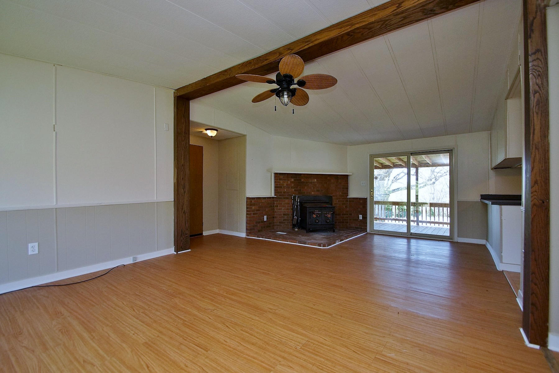 164 Tabernacle Road Penhook, VA 24137 - Photo 9 of 46 an empty room with wooden floor a ceiling fan a fireplace and windows