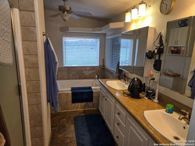 a bathroom with a granite countertop sink a mirror and a bathtub
