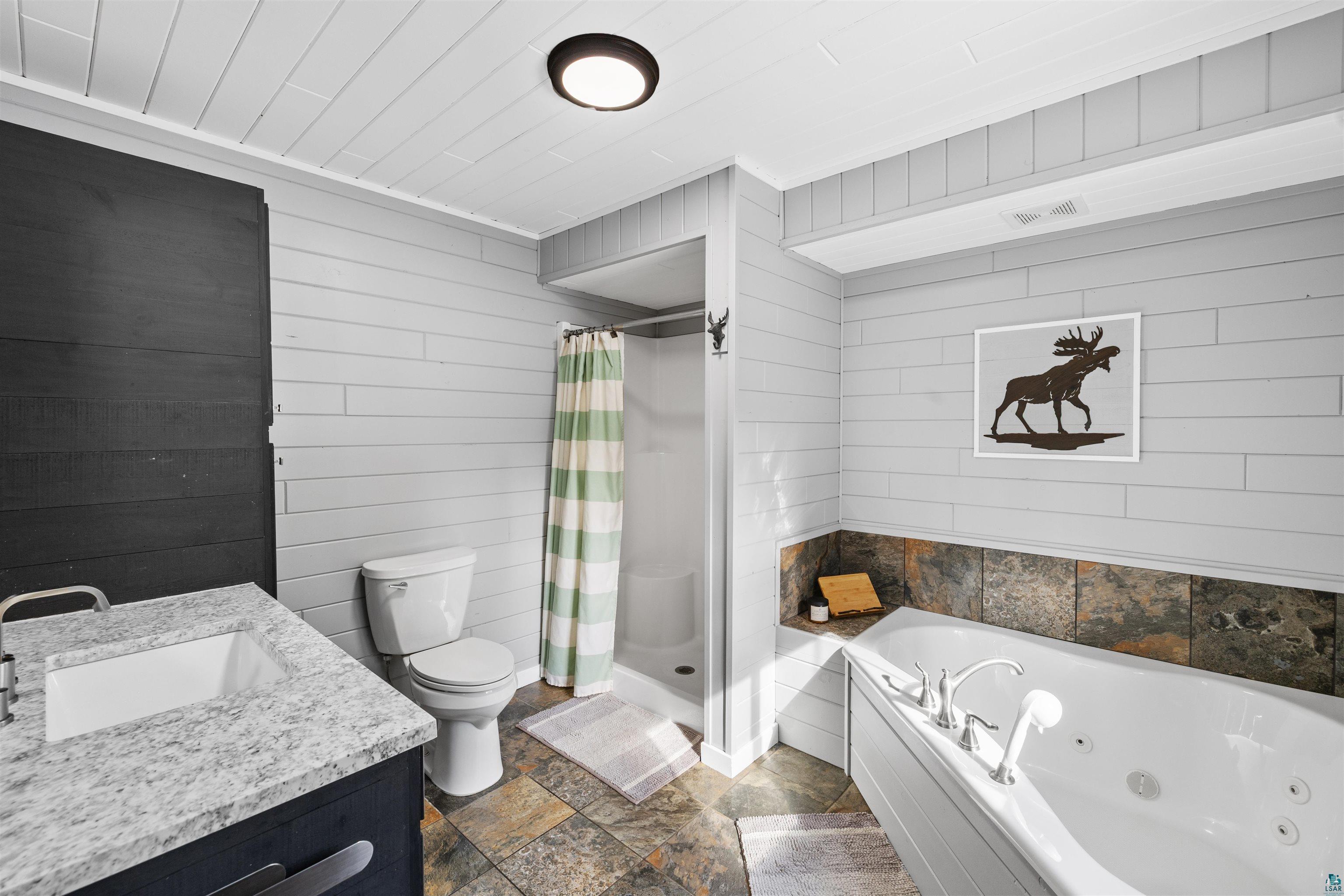 13462 Villa Road Ely, MN 55731 - Photo 22 of 68 Primary bathroom with a shower stall, tile flooring, vanity, a whirlpool tub, and wood walls