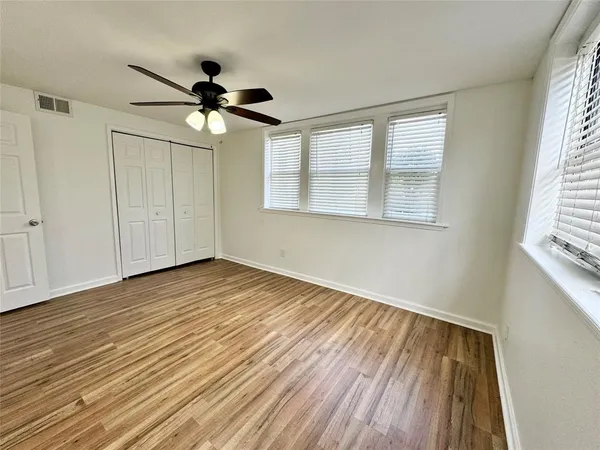 an empty room with wooden floor and windows
