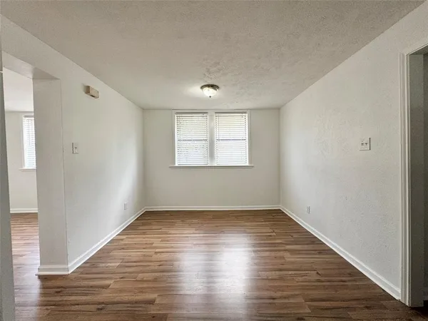 an empty room with wooden floor chandelier fan and windows