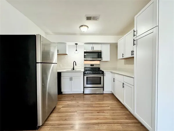 a kitchen with white cabinets stainless steel appliances and sink