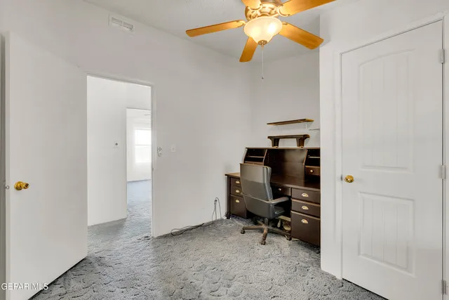 an empty room with windows and fan