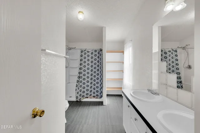a view of an empty room with chandelier fan and fire place