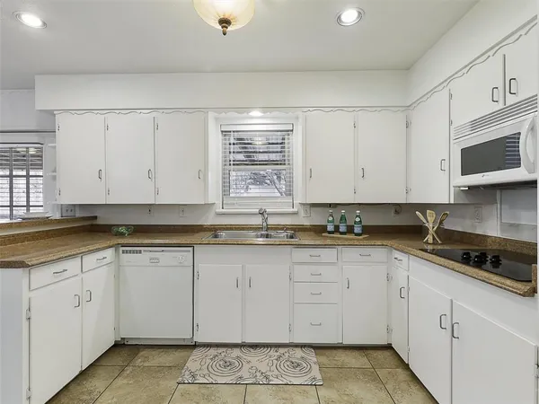 a kitchen with white cabinets sink and window